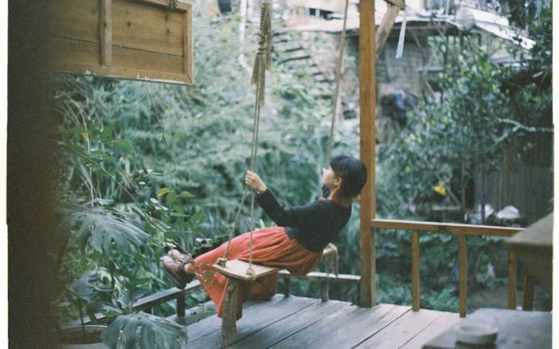 Woman in a garden sitting on a swing, enjoying nature and tranquility.