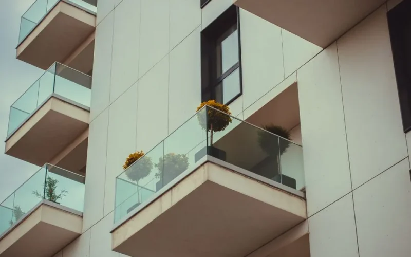 A modern apartment building's glass balconies with potted plants create a sleek urban facade.