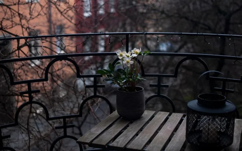 A charming balcony with a potted plant and decorative lantern in Stockholm. Ideal for lifestyle or architectural themes.