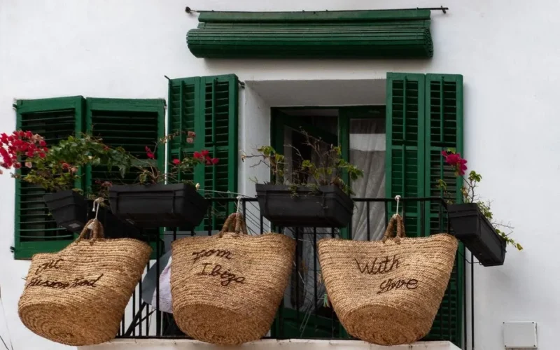 A picturesque balcony in Ibiza adorned with straw baskets and vibrant flowers.
