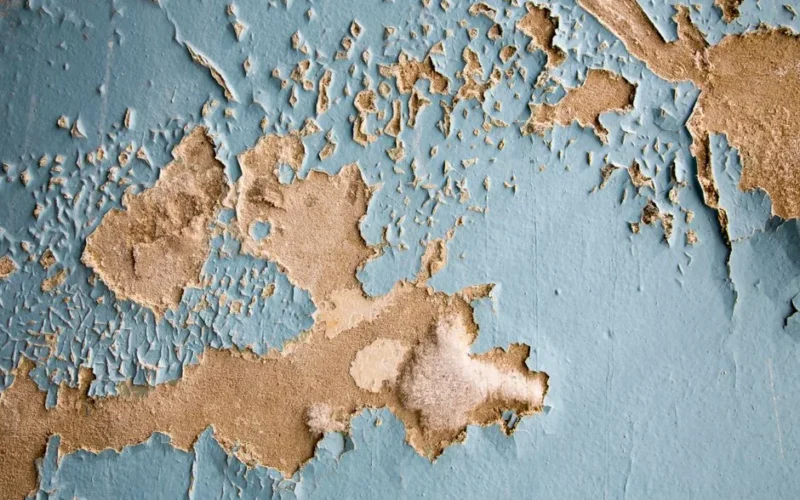 Detailed texture of cracked and peeling blue paint on an old wall surface. Perfect for background.