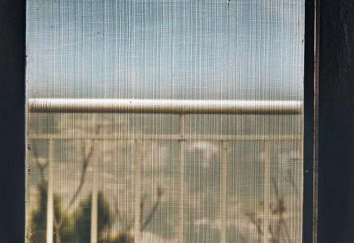 A minimalist view through a mesh screen showing railings outdoors.