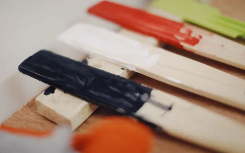 Close-up of colorful paint swatches applied on wooden sticks, showcasing different hues.