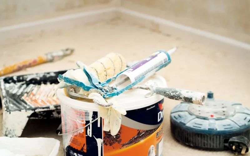 A collection of painting tools and materials for home renovation, featuring paint rollers and a bucket.
