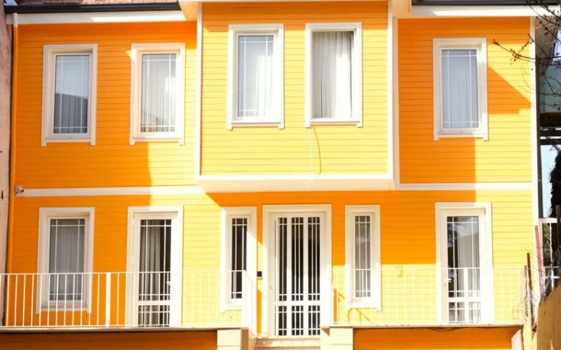 A bright yellow house exterior with white framed windows and door.