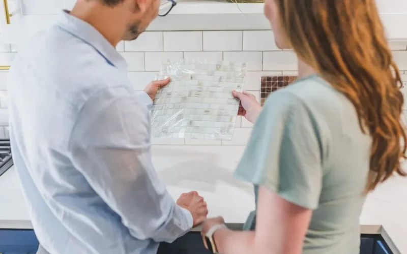 A man and woman selecting tile designs for a kitchen remodeling project.