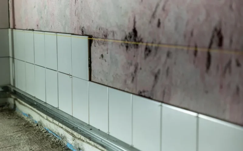 Close-up of partially tiled wall in a construction area, showcasing incomplete renovation work.