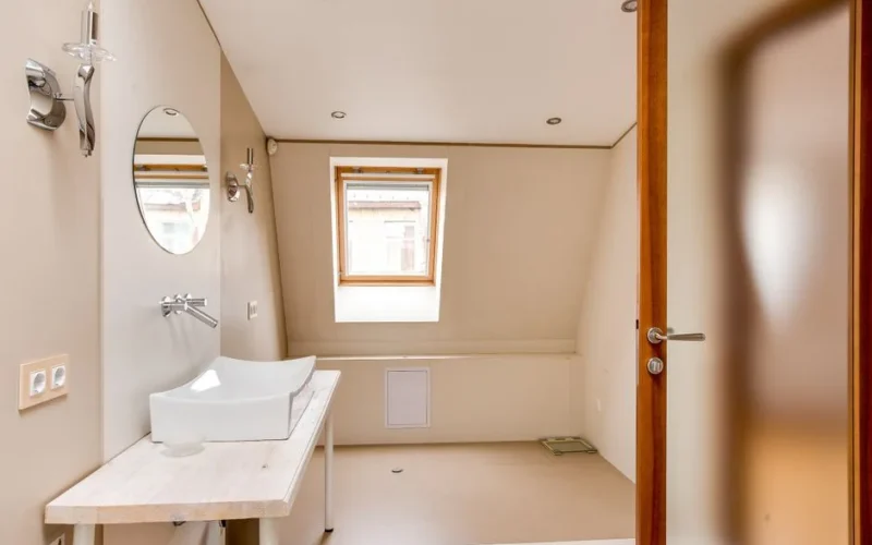 A stylish and spacious attic bathroom featuring a minimalist design, skylight, and modern fixtures.