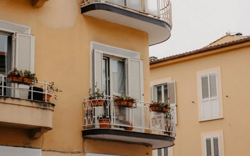 A close-up view of charming balconies adorned with potted plants on a yellow residential building.