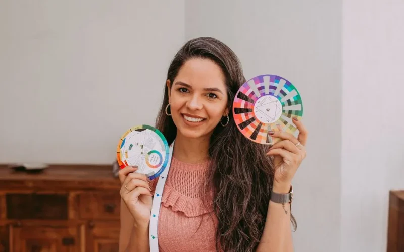 Smiling woman holding colorful palette wheels inside a room.