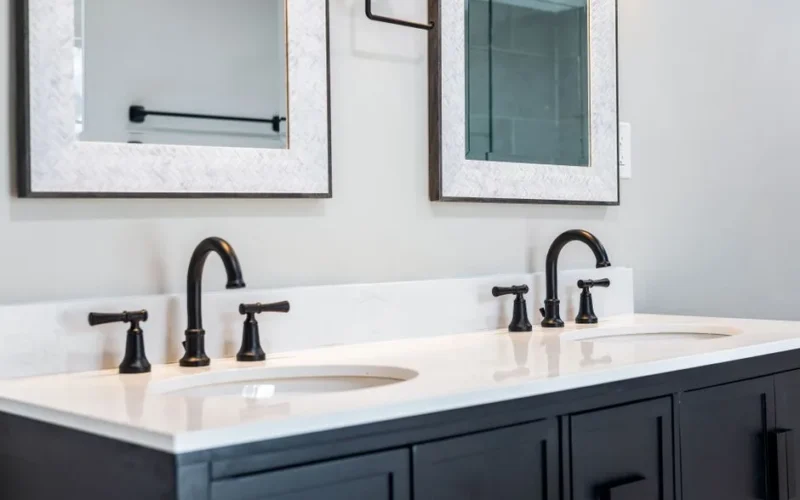 Sleek bathroom vanity featuring a double sink setup with stylish black faucets and framed mirrors.