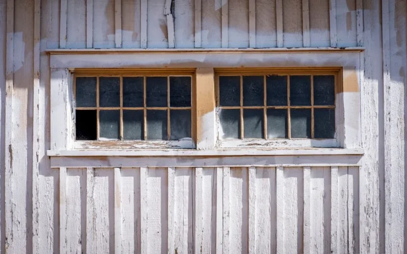 Close-up of a vintage wooden window on a rustic building facade with peeling paint.
