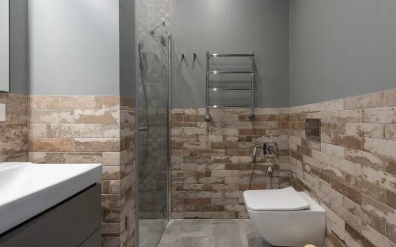 Stylish contemporary bathroom featuring a glass shower and brick accent wall.