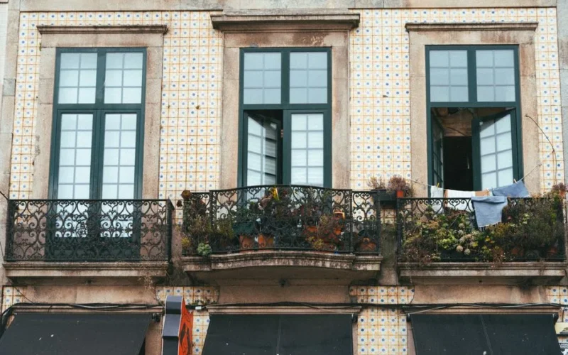 Decorative iron balcony and tiled façade of a building in Porto, Portugal.