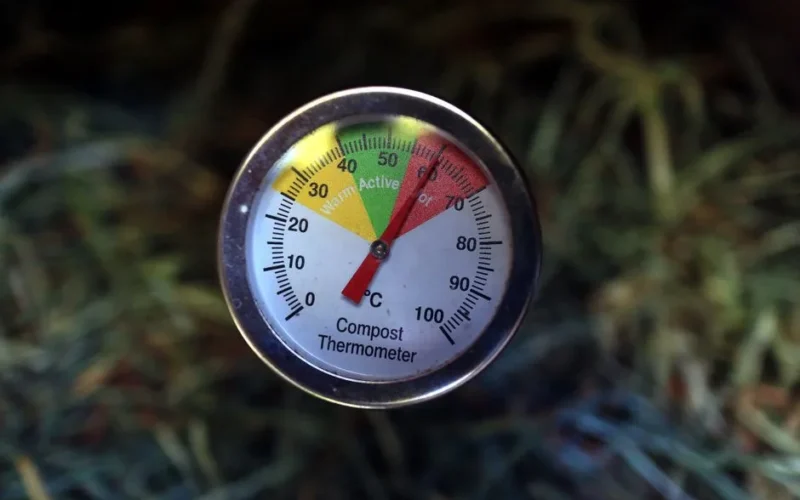 Close-up of a compost thermometer showing active temperature in a compost pile.