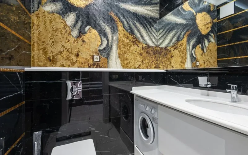 Elegant modern bathroom featuring a striking mosaic wall design with a white sink and washing machine.